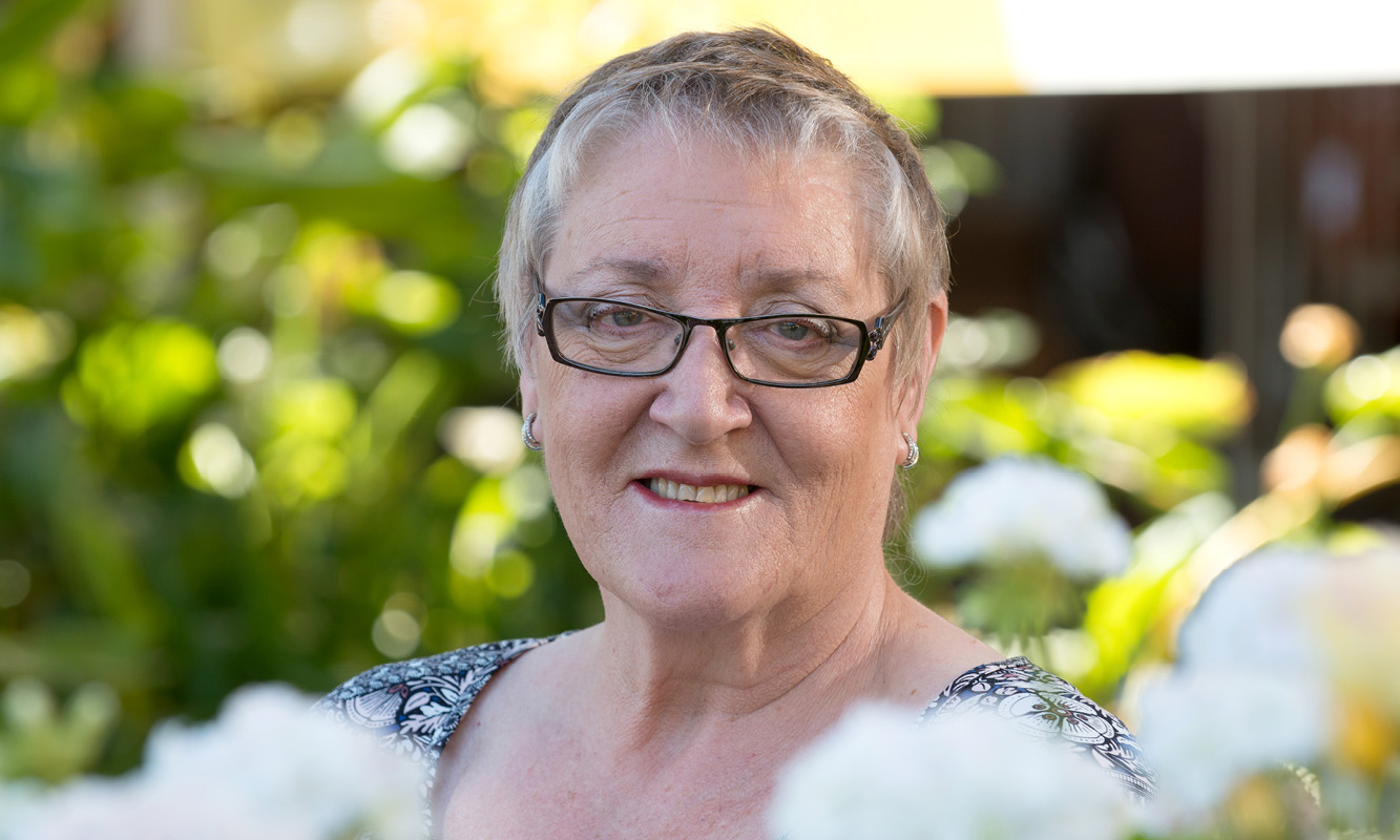 Photo of Margaret with green background and white flowers in foreground has left a gift in her will to Cancer Council SA