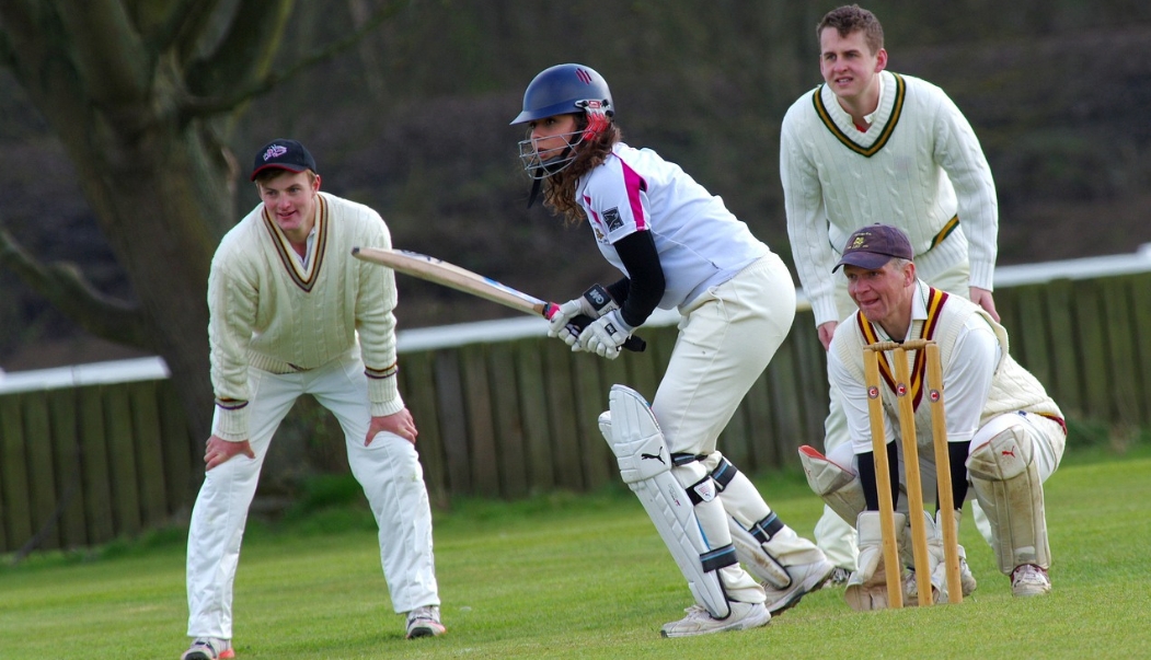 4 people playing community cricket in full uniform