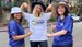 three women with hats on smiling and wearing The March Charge t-shirts