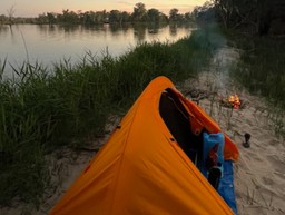 An orange tent on a river bank